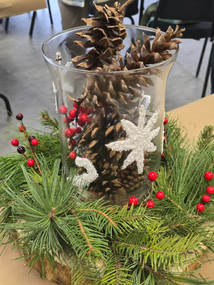 table centerpiece made with greenery and a vase filled with pinecones 